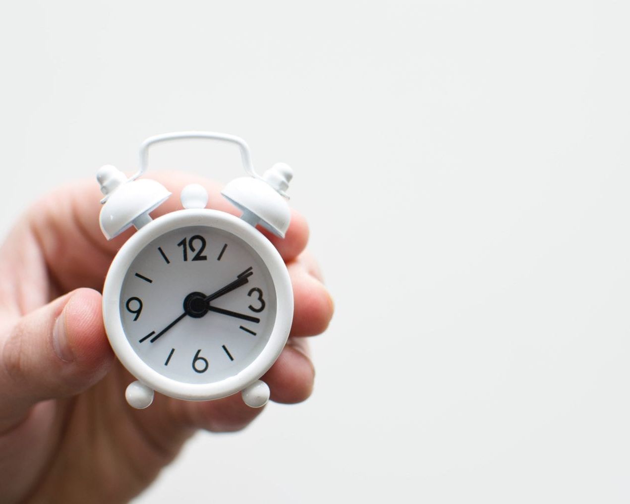 A person holding a small alarm clock.