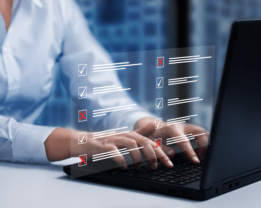 Hands typing on a laptop with a digital checklist overlay representing online exam marking and automated assessment tools.