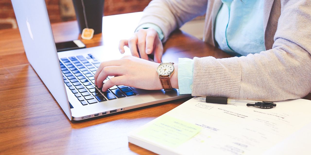 Person on laptop with notebook