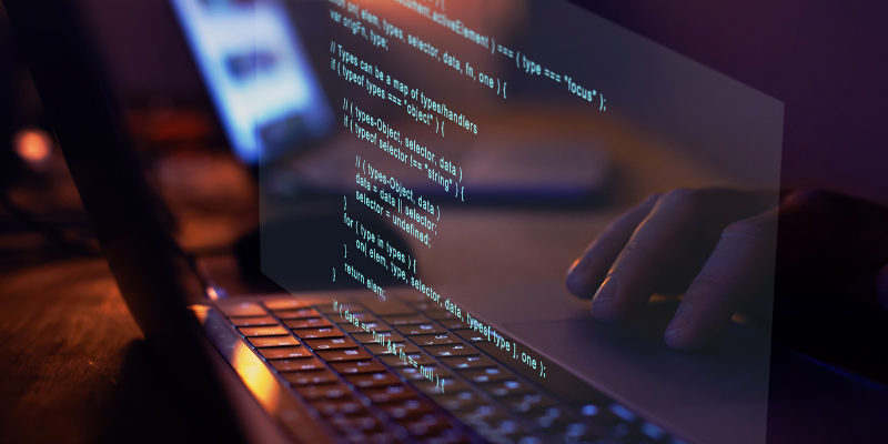 Developer writing code on a laptop to build a custom exam platform