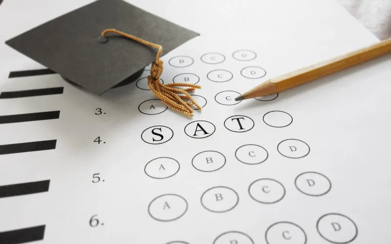 Multiple-choice test sheet marked SAT with a pencil and graduation cap symbolising a high-stakes summative assessment