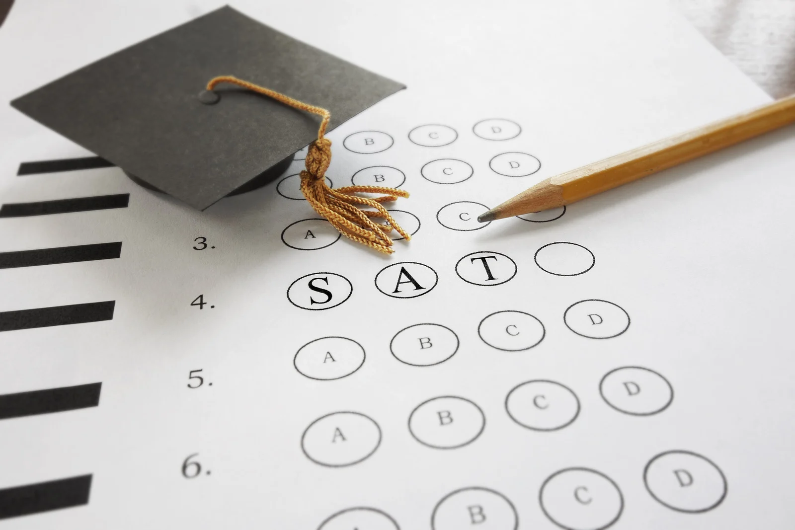 Multiple-choice test sheet marked SAT with a pencil and graduation cap symbolising a high-stakes summative assessment